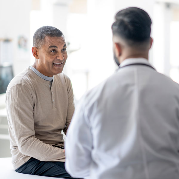 mature male speaking with doctor in exam room