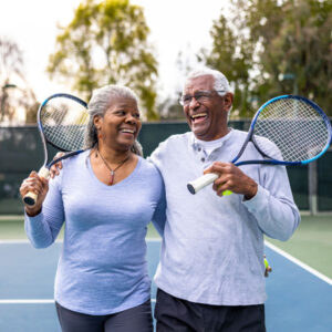 senior couple smiling after a game of tennis